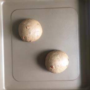 卷起面团，盖上保鲜膜松弛15分钟，然后把面团平均分为两份，每一份都滚圆，放入烤盘内，进行第二次发酵