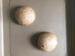 卷起面团，盖上保鲜膜松弛15分钟，然后把面团平均分为两份，每一份都滚圆，放入烤盘内，进行第二次发酵