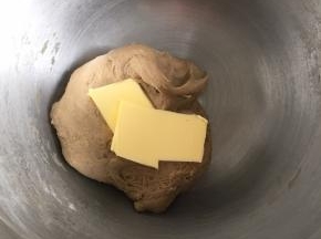 把面团揉成摸上去有点粘，但是不会粘到面团在手上的状态，加入软化的黄油，继续揉面