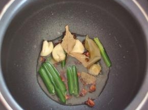 将电饭煲里倒入油，放入葱、姜、蒜、花椒、八角、香叶、白芷，按下煮饭键，合上盖子，直至油热后将香料炸香。