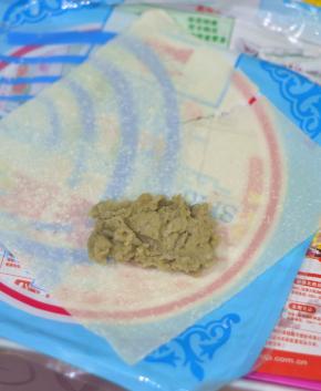取一张春卷皮，如图位置摆放，将馅铺在皮的三分之二处的中间。