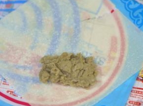 取一张春卷皮，如图位置摆放，将馅铺在皮的三分之二处的中间。