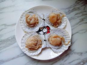 将刷干净的扇贝壳放入盘子里，再把泡软的粉丝放在贝壳中间，再把腌制好的扇贝肉放在粉丝的上面。