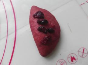 在将红色面团对折一下，再次加入少量蔓越莓