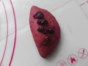 在将红色面团对折一下，再次加入少量蔓越莓