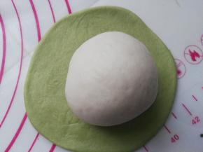 将包好的白色面团放在绿色面皮中间。