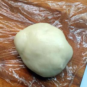 在手上抹一点油，然后取出面团放在面板上，面板上放上一张保鲜膜，以免会粘上