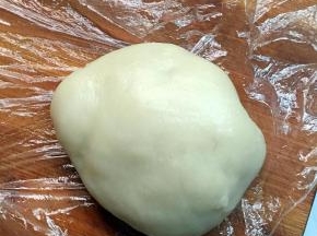 在手上抹一点油，然后取出面团放在面板上，面板上放上一张保鲜膜，以免会粘上