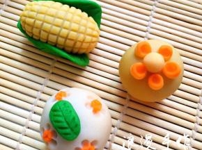 玉米-绿茶桃山皮做玉米的叶子，用牙签压出纹路，黄金桃山皮包好馅后捏成椭圆形，再用牙签压出小格子，用少许水沾好。也可以沾好叶子后再压纹路。剩下两个圆果子是沾上胡萝卜小圆片后用筷子在周围压5个圓印，再沾上一片叶子