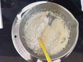 刮刀从2点钟方向插入，刮至8点钟方向，舀起一大勺黄油，移至盆中央，甩掉黄油，左手将盆逆时针转动一下。