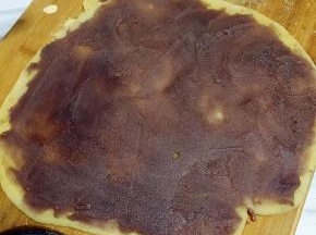 在面板上和面团上撒上少许炒熟的黄豆面，用擀面杖擀成方形，均匀抹上豆沙馅；