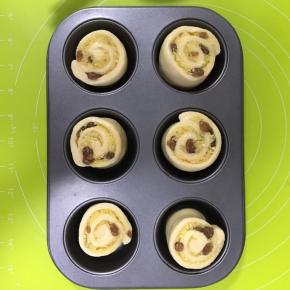 6连不粘杯子蛋糕模具内壁抹上适量融化黄油，放入面团卷，切面朝上