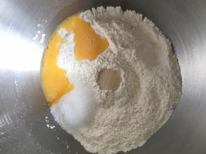 盆哪倒入高筋面粉和低筋面粉，混合均匀，中间挖一小孔，倒入活性干酵母，盐和糖对角线放置，倒入全蛋液