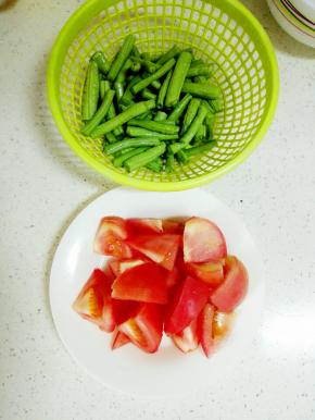 长豇豆洗净切段备用，西红柿洗净，切小块备用