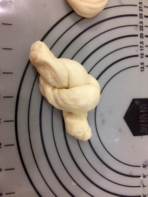 右手的面条压在左手上，然后左手的面条从上面圈里穿过，像图片一样