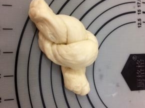右手的面条压在左手上，然后左手的面条从上面圈里穿过，像图片一样