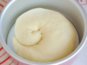 轻轻将面团卷起，盘在六寸蛋糕圆模中，放入烤箱发酵40分钟左右，同时烤箱内部要放一碗开水。