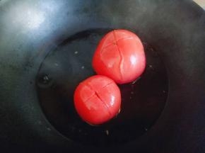 把番茄切十字刀，放入沸水锅中煮2分钟捞出。