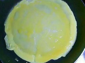 倒入适量打散的鸡蛋液（可直接把鸡蛋打在上面，用勺子摊均匀）