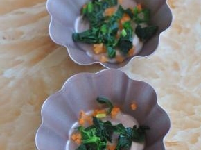 将菠菜捏去水分，与胡萝卜碎放入容器底部。