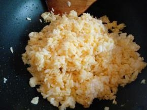 将用蛋黄拌均匀的米饭倒入锅中，小火翻炒。