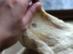 伸拉面团，有光滑的破洞形成，代表面团已揉好，盖保鲜膜发酵待面团涨至2倍大