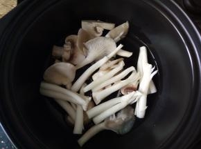 取一个砂锅，底部装入少许菌菇。