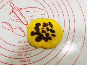 取一黄色面团，压扁，放入少量的蔓越莓；