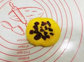 取一黄色面团，压扁，放入少量的蔓越莓；