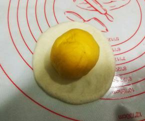 将黄色面团收口朝上，放置在白色面团上；