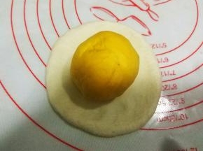 将黄色面团收口朝上，放置在白色面团上；