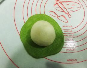 把白色面团收口朝上，放在绿色面团上；