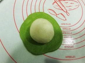 把白色面团收口朝上，放在绿色面团上；