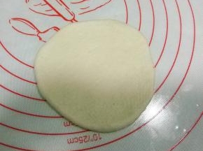 取一白色面团，擀成圆形，尽量中间薄，边缘厚些；