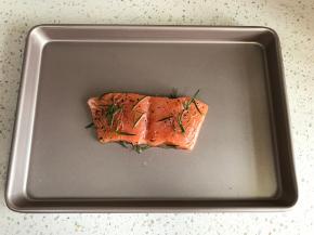 将鱼取出，放入烤盘，腌制出的汁水也倒在鱼肉上。