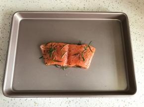 将鱼取出，放入烤盘，腌制出的汁水也倒在鱼肉上。