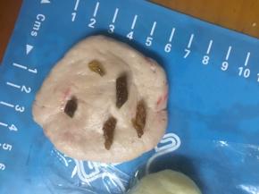 红色面团按平放入切碎的葡萄干