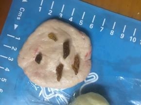 红色面团按平放入切碎的葡萄干