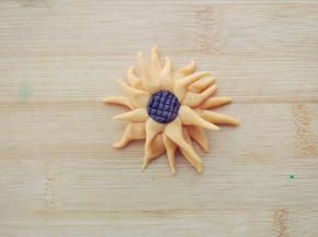 揪一小块橘色面团，搓成雨滴状，放射性粘合在一起，中间用可可面团压出花纹