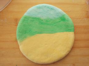 将蓝色、绿色和黄色搓成长条，并排在一起，包住白色面团，压扁后放在一边进行二次发酵