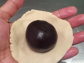 取一份桃山皮，压成中间厚边缘薄的薄片，放入月饼陷