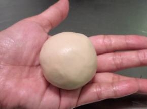 借助切片拿起饼皮，收口收紧，两手合拢，稍用力将月饼搓圆搓光滑