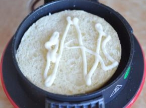 早餐机先预热几分钟，然后将底片的面包片放入早餐机底部，挤上沙拉酱。