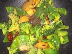 再放入西兰花，青椒，将这些配菜炒至5分熟即可，不要炒得太熟，因为这些等会还要再烤