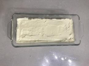 把过筛好的低筋面粉，倒入黄油糊中用刮刀翻拌均匀，再用刮刀把面糊装入法涪客玻璃磅蛋糕模具，表面用刮刀刮平。