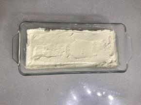 把过筛好的低筋面粉，倒入黄油糊中用刮刀翻拌均匀，再用刮刀把面糊装入法涪客玻璃磅蛋糕模具，表面用刮刀刮平。