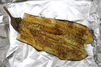 再烤好的茄子从中间切开出来，但不要切断开了，蒂也要留着，把刚刚调好的酱汁均匀的涂在表面上，