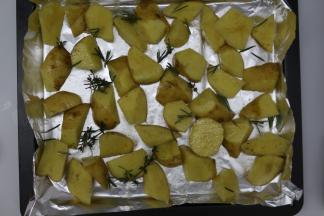 烤盘垫上锡纸，把薯角平铺在烤盘里，再在表面放上百里香和迷迭香