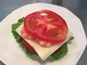 贝果从侧面对切，准备好配料：生菜洗净擦干，番茄切片，虾炒熟。随心意摆放在贝果上