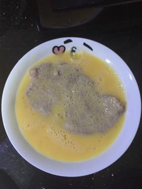 把猪排上多余的淀粉拍掉，放放鸡蛋液里裹上蛋液